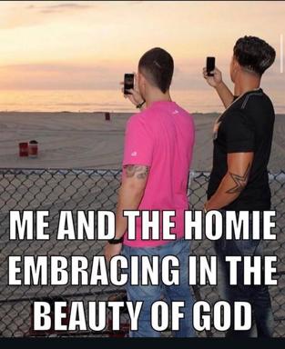 Two men at a beach sunset, both photographing the scene on their phones rather than watching it. Impact-font text reads "ME AND THE HOMIE EMBRACING IN THE BEAUTY OF GOD"—commentary on mediated experience and the phone-culture disconnect.