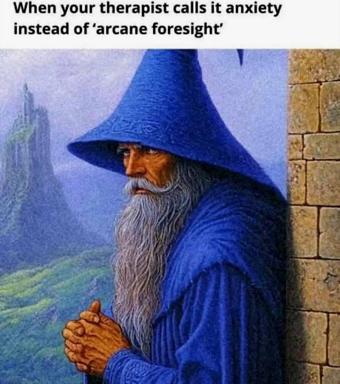 A blue-robed wizard with a pointed hat and long grey beard, standing in a gothic tower doorway overlooking a misty landscape, captioned with the joke: "When your therapist calls it anxiety instead of 'arcane foresight.'"
