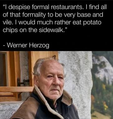 Werner Herzog dismisses formal restaurants with deadpan contrarianism, preferring potato chips on a sidewalk—deadpan food-culture satire.