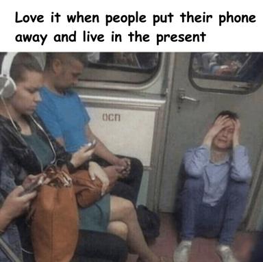 Text-over-image meme satirizing the irony of mindfulness culture. A crowded transit car shows phone-absorbed passengers while one woman looks distressed with hands to head, a darkly relatable commentary on collective digital distraction.